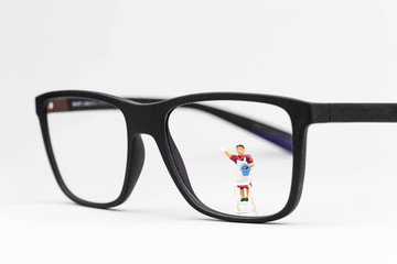 Miniatur Putzfrau reinigt Glas einer Brille 