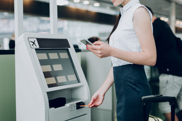 Checking mobile bank. Young female is using mobile app on smartphone, while taking off plastic card...