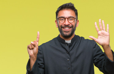 Adult hispanic catholic priest man over isolated background showing and pointing up with fingers number six while smiling confident and happy.