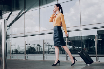 Im leaving today. Full length portrait of business lady with suitcase talking on phone at the...