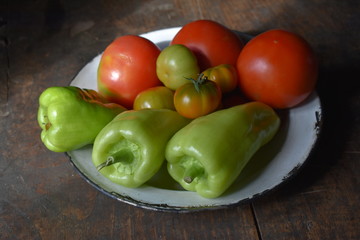 plato antigua con tomates pequeños, pimientos verdes todo de la huerta 