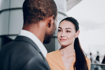 Pleasant meeting. Close up portrait of two people meeting each other. Focus on graceful girl in yellow shirt looking candidly at male who stands back to the camera