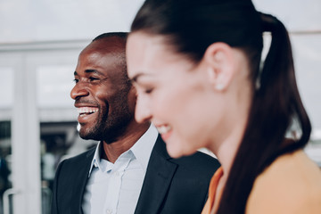 Sounds funny. Close up portrait of two people having fun. Focus on man with wide smile and cheerful eyes