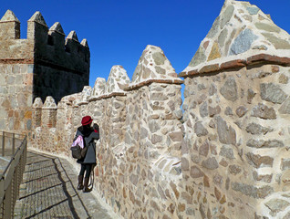 One female tourist taking some photo from the medieval city walls of Avila, Spain