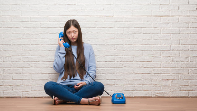 Young Chinese woman calling using vintage telephone with a confident expression on smart face thinking serious