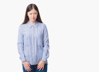 Young Chinese woman over isolated background skeptic and nervous, frowning upset because of...