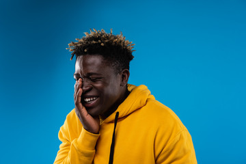 Funny moment. Portrait of young male with closed eyes chuckling at something. He is wearing yellow...