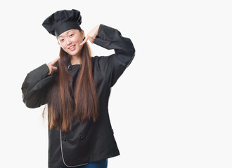 Young Chinese woman over isolated background wearing chef uniform smiling confident showing and pointing with fingers teeth and mouth. Health concept.