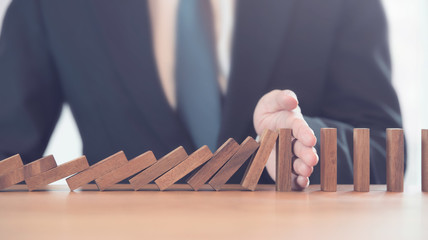 Problem Solving, Close up hand of businessman stopping falling blocks on table.