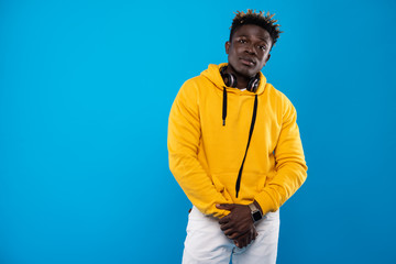I am cool. Portrait of handsome guy with headphones. He is wearing stylish clothes and looking at camera with calm expression. Isolated on blue background