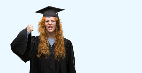 Young redhead student woman wearing graduated uniform annoyed and frustrated shouting with anger, crazy and yelling with raised hand, anger concept