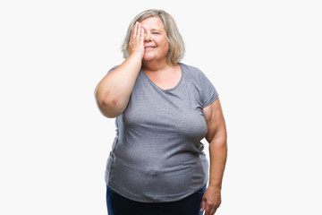 Senior plus size caucasian woman over isolated background covering one eye with hand with confident smile on face and surprise emotion.