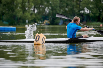 Young man racing on the lake in his canoe, he is on rowing competition