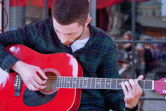 A Busker singing and playing guitar on the streets of old European city. Caucasian man playing the guitar outdoors.