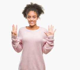 Young afro american woman wearing winter sweater over isolated background showing and pointing up with fingers number eight while smiling confident and happy.