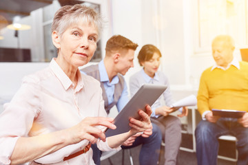 Alte Frau mit Tablet Computer bei Business Meeting