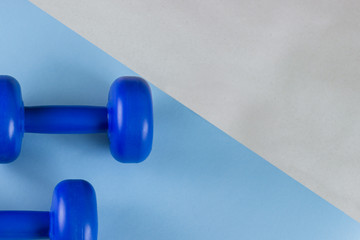 Bright blue dumbbells on a blue background. Healthy lifestyle, the concept of losing body weight....