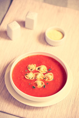 Homemade fresh cream of tomato soup with tortellini and fresh oregano, photographed with natural light (Selective Focus in middle of the soup) (Digitally Altered: Toned Image)