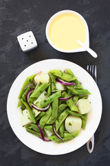 Green bean, potato and red onion salad with parsley, hollandaise sauce on the side, photographed...