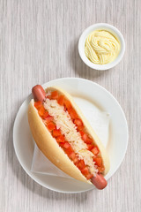 Chilenische Completo Clasico (klassisch) oder Aleman (deutsch) Hotdog Sandwich gefüllt mit Würstchen, Tomate und Sauerkraut, Mayonnaise an der Seite, fotografiert mit natürlichem Licht 