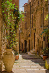 Fototapeta na wymiar Old courtyard in Pitigliano with vases with flowers on the stairs