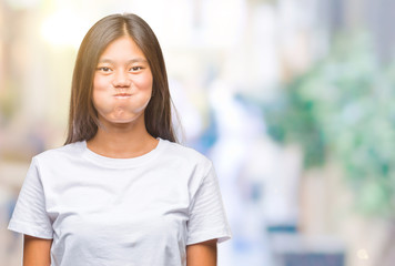 Young asian woman over isolated background puffing cheeks with funny face. Mouth inflated with air,...
