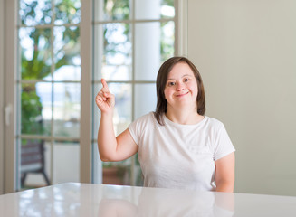 Down syndrome woman at home very happy pointing with hand and finger to the side