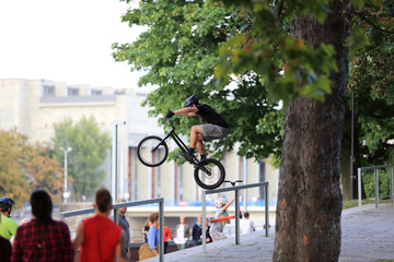 Fototapeta Młody mężczyzna skacze na rowerze przez barierkę na Wrocławskim bulwarze. obraz