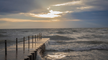 Obraz premium Concrete pier leading out to epic waves