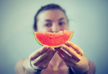 Junges Mädchen hält sich ein Stück Melone vor das Gesicht, Konzept