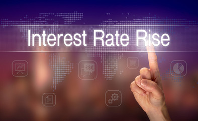 A hand selecting a Interest Rate Rise business concept on a clear screen with a colorful blurred background.