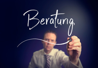 A businessman writing a Consultation "Beratung" concept in German with a white pen on a clear screen.