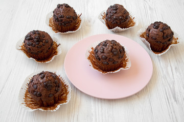 Chocolate muffins, side view. White wooden background.