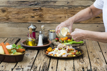 Manos de persona preparando patatas aliñadas.