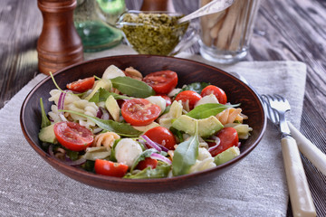 Homemade salad of cherry tomatoes, arugula, mozzarella, quail eggs and pasta in a ceramic plate
