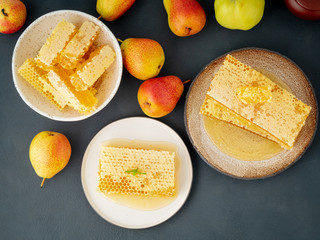 Three plate with honey in honeycomb, close-up, on brown ceramic plate, on gray stone table, top view