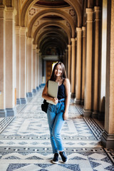 Young asian woman student holding laptop at college walking to the classes in university hall