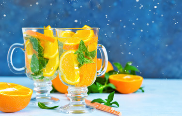 Cold summer drink. Lemonade with mint and orange on a blue background.