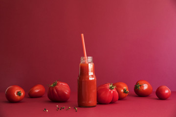 Fresh and summer tomato smoothies and tomato fruits and pepper on the red background. Many vitamins...