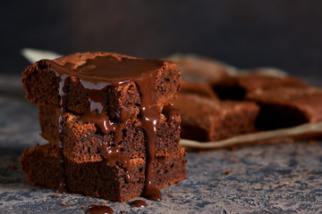 Brownie is a classic American dessert. Pie with chocolate sauce on a dark background.