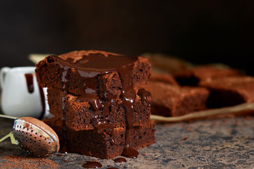 Brownie is a classic American dessert. Pie with chocolate sauce on a dark background.