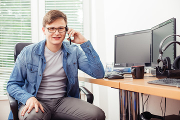 Happy man talking on the mobile phone in the office