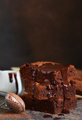 Brownie is a classic American dessert. Pie with chocolate sauce on a dark background.