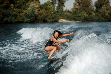 Brunette woman wakesurfing on board down the blue water