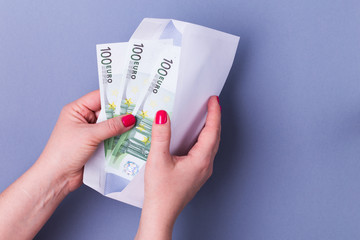 Woman hands holding envelope with cash. Euro banknotes.