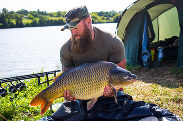 Happy angler with carp fishing trophy