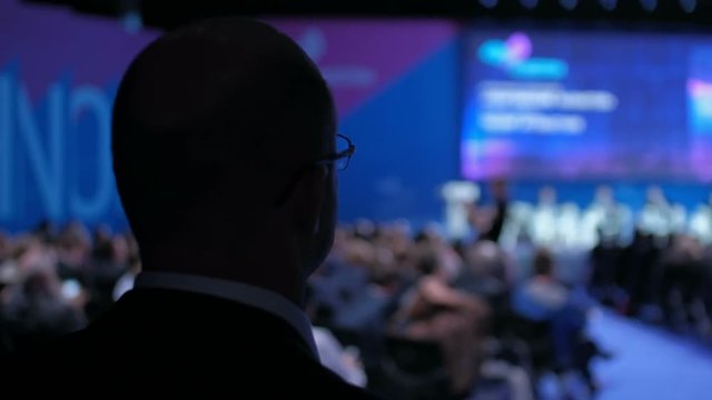 Businessman in a conference hall is looking at speakers presentation.