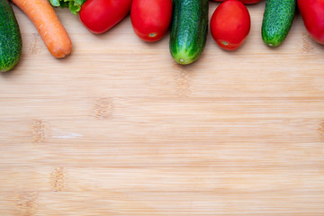 Vegetables on wooden cutting board. Vegetables: lettuce, tomatoes, cucumbers, carrots.
