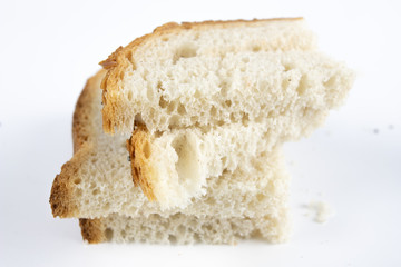 A slice of bread on a white kitchen table. Bread with poppy seeds cut into pieces.