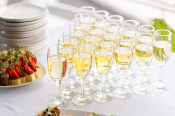 Bartender pouring champagne or wine into wine glasses on the table in restaurant. solemn wedding ceremony or happy new year banquet